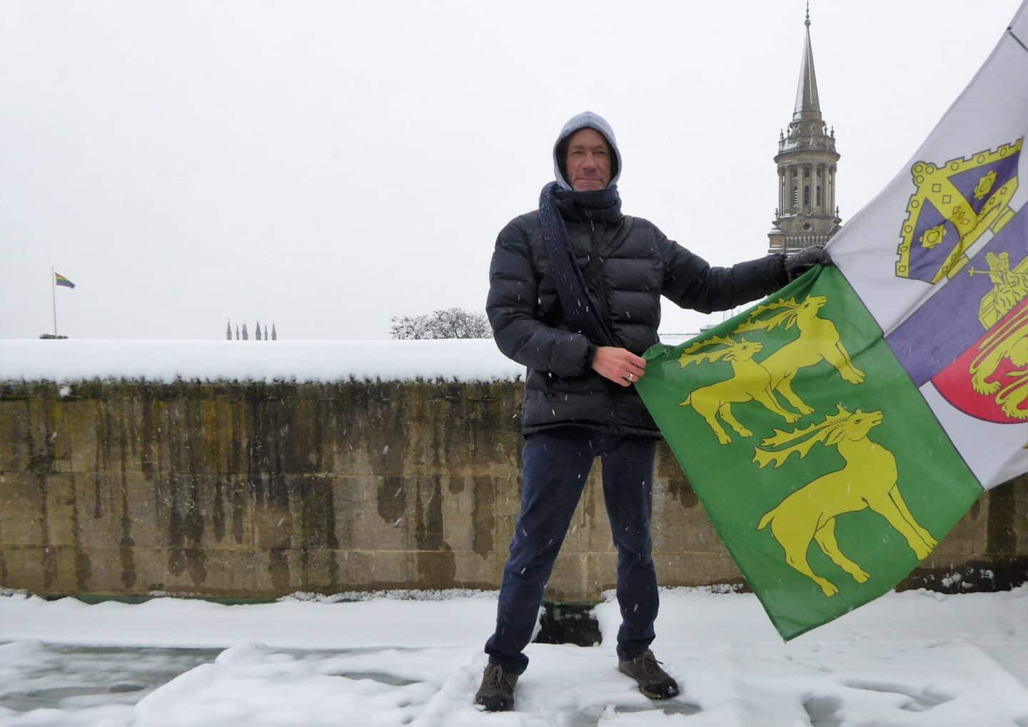 Bob Weatherhead holding flag on rooftop of building in Front Quad