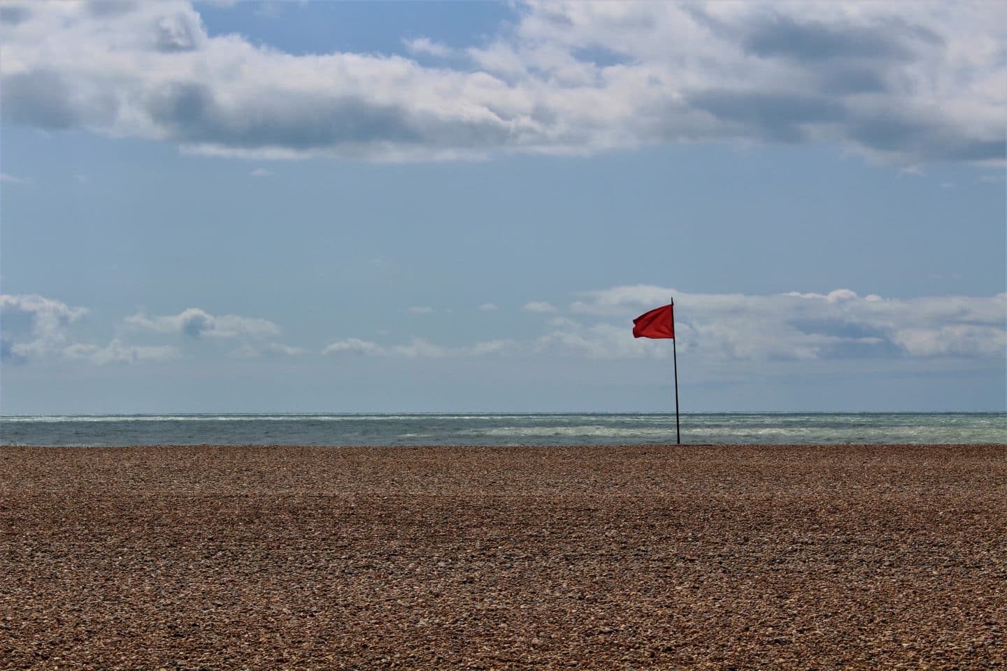 A red flag on a deserted beach