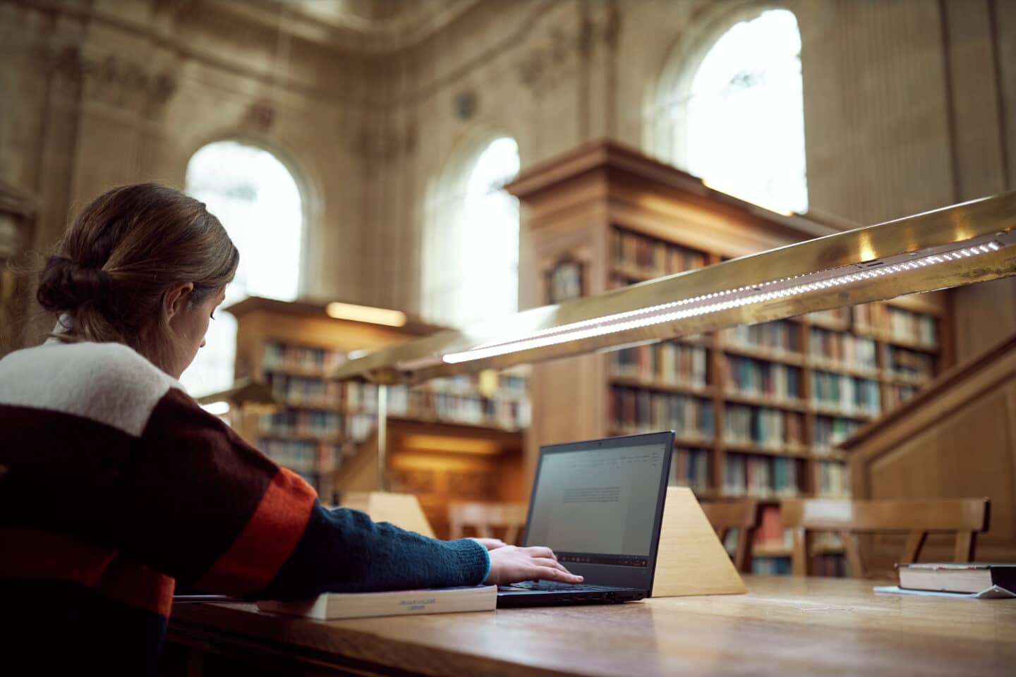 Student sitting at desk in Library using her laptop