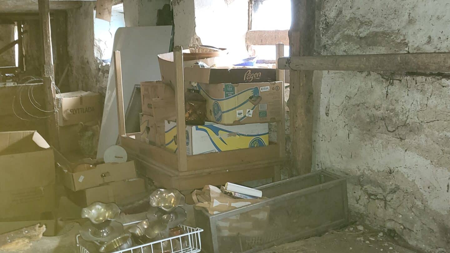 Photo of the inside of an old barn in Sweden with boxes of random objects in the foreground