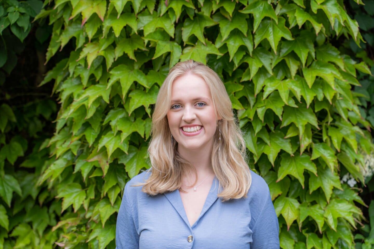 Photo of Hannah Edwards standing in front of green ivy