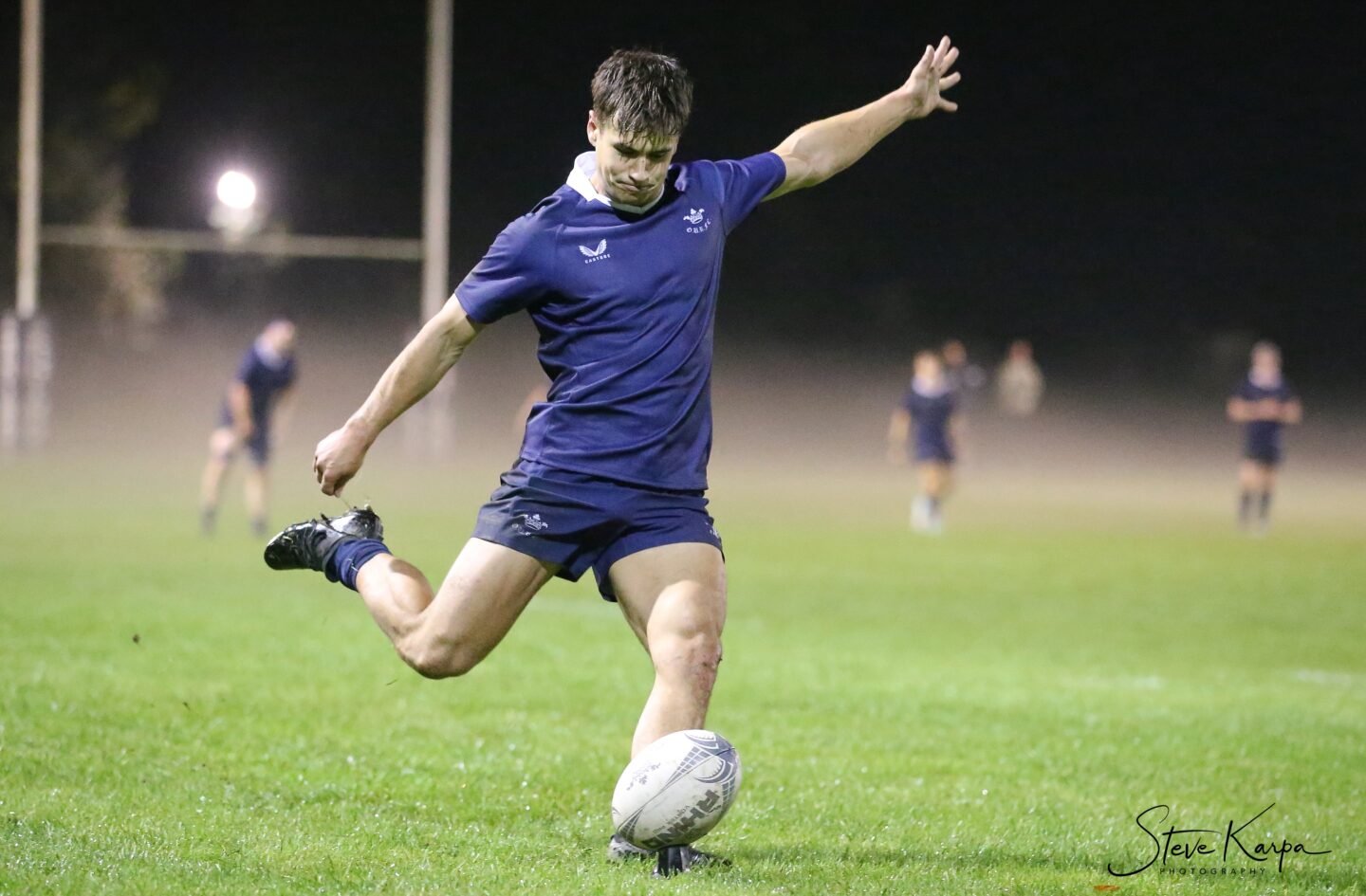 Photo of Harry Bridgewater running with the ball at his feet in a match. Other teammates are blurred in the distance behind him.