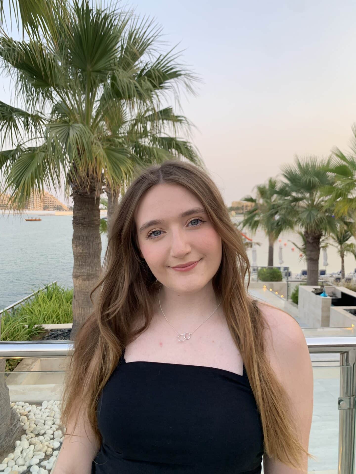 Photo of Charlotte Paylor wearing a black top standing in front of palm trees