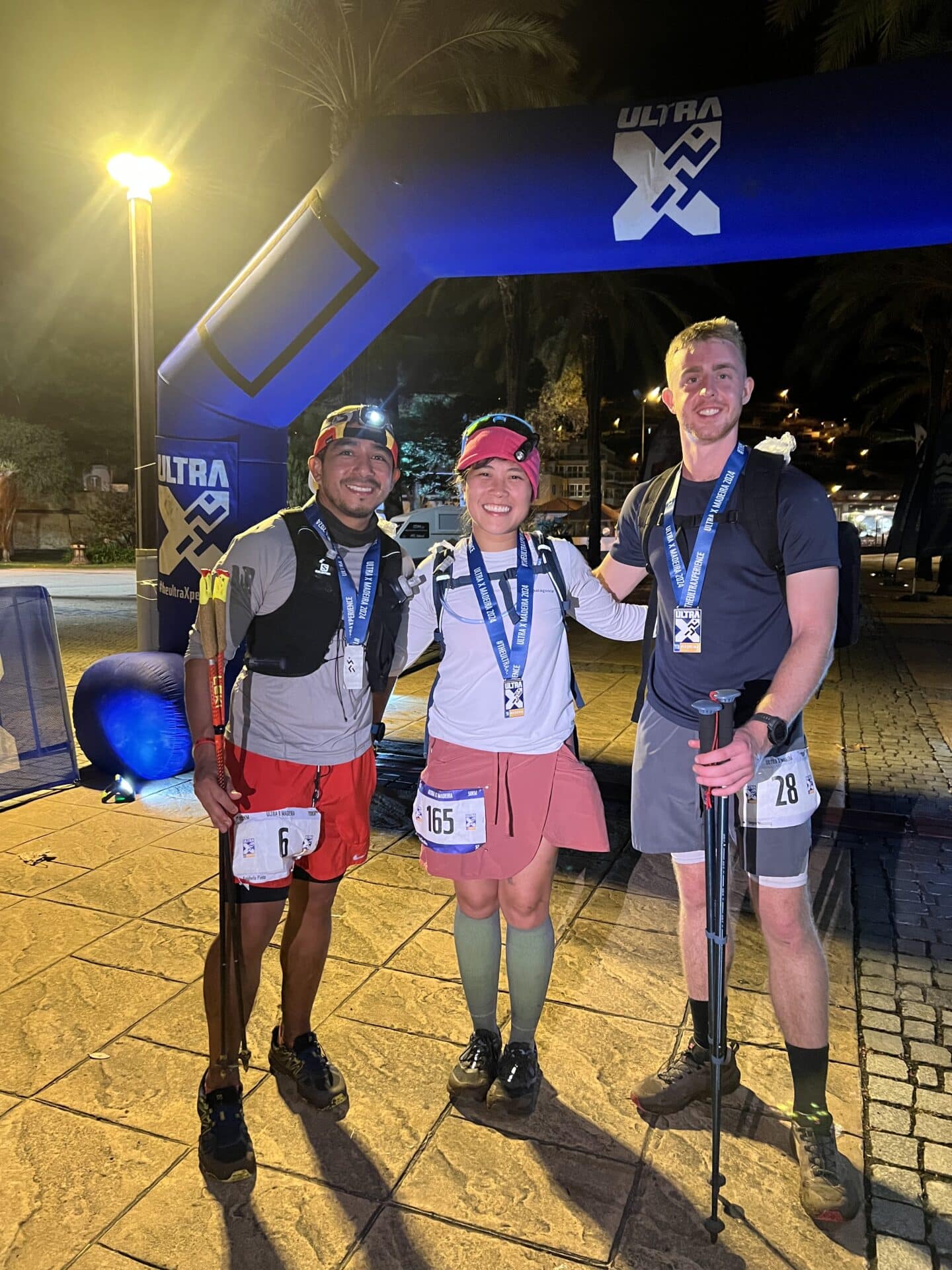 Micon Garvilles in the middle of two other runners at the finish line of the ultramarathon with medals around their necks