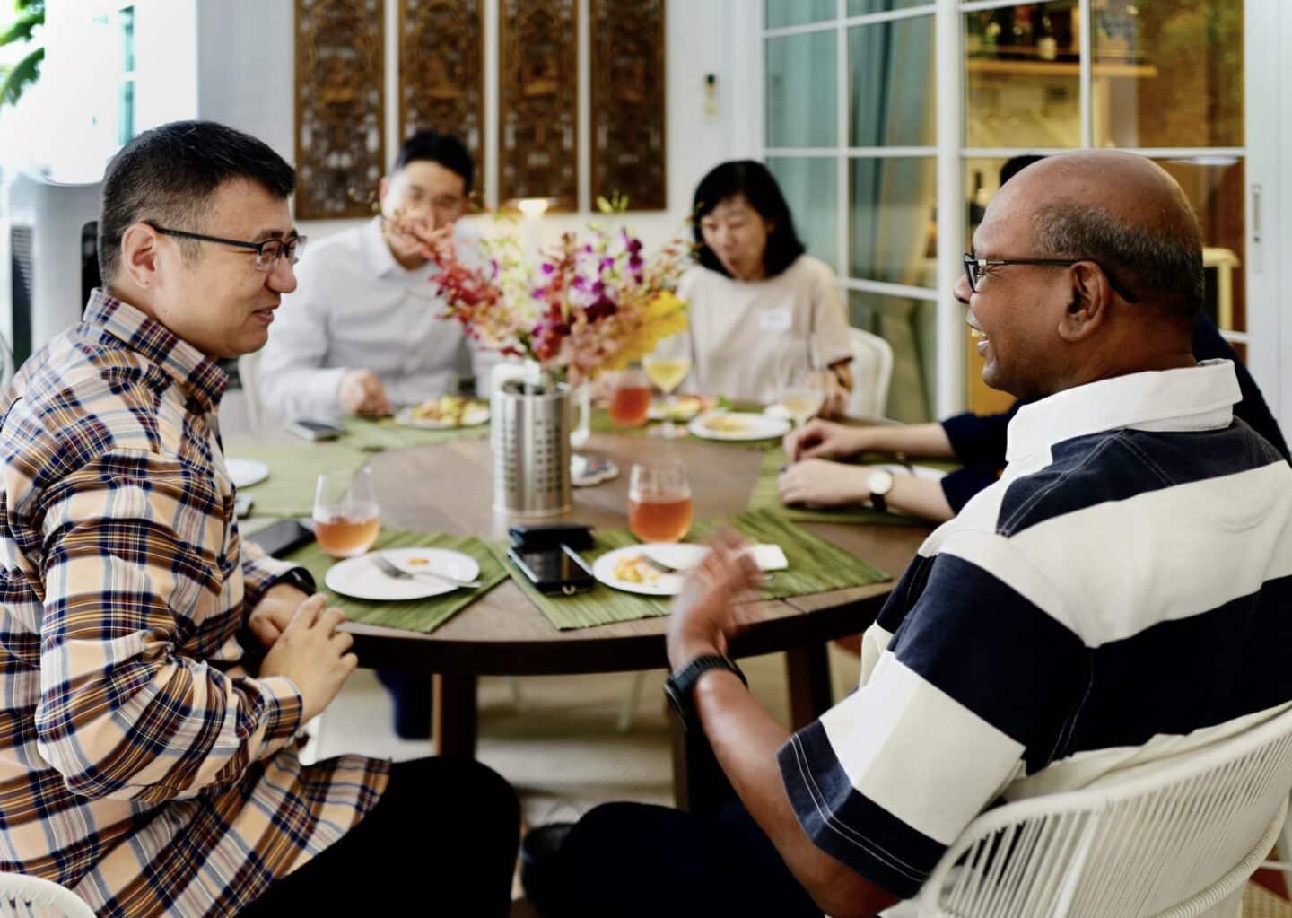 alumni sitting around the table laughing at toasts across the coasts Singapore
