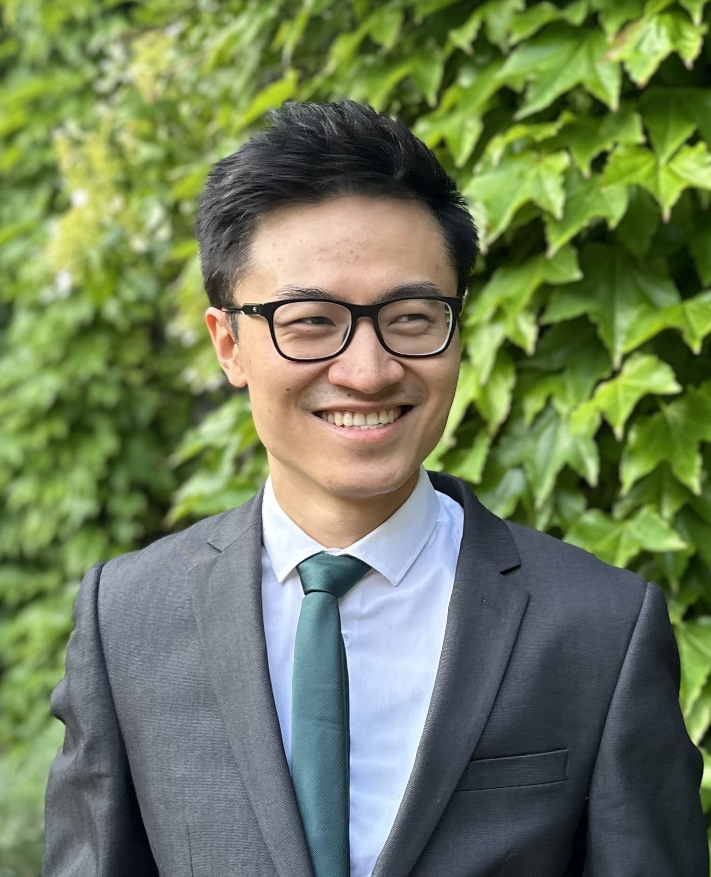 Photograph of Joshua (Yifan) Li, wearing a suit and glasses