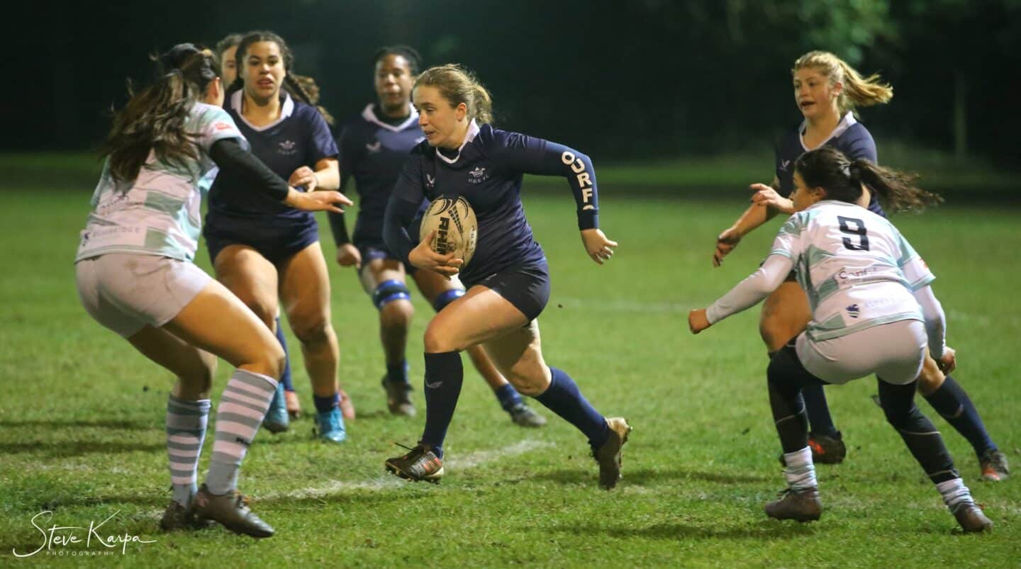 Action photo of Katie Hains running with the ball in a match surrounded by players from both teams