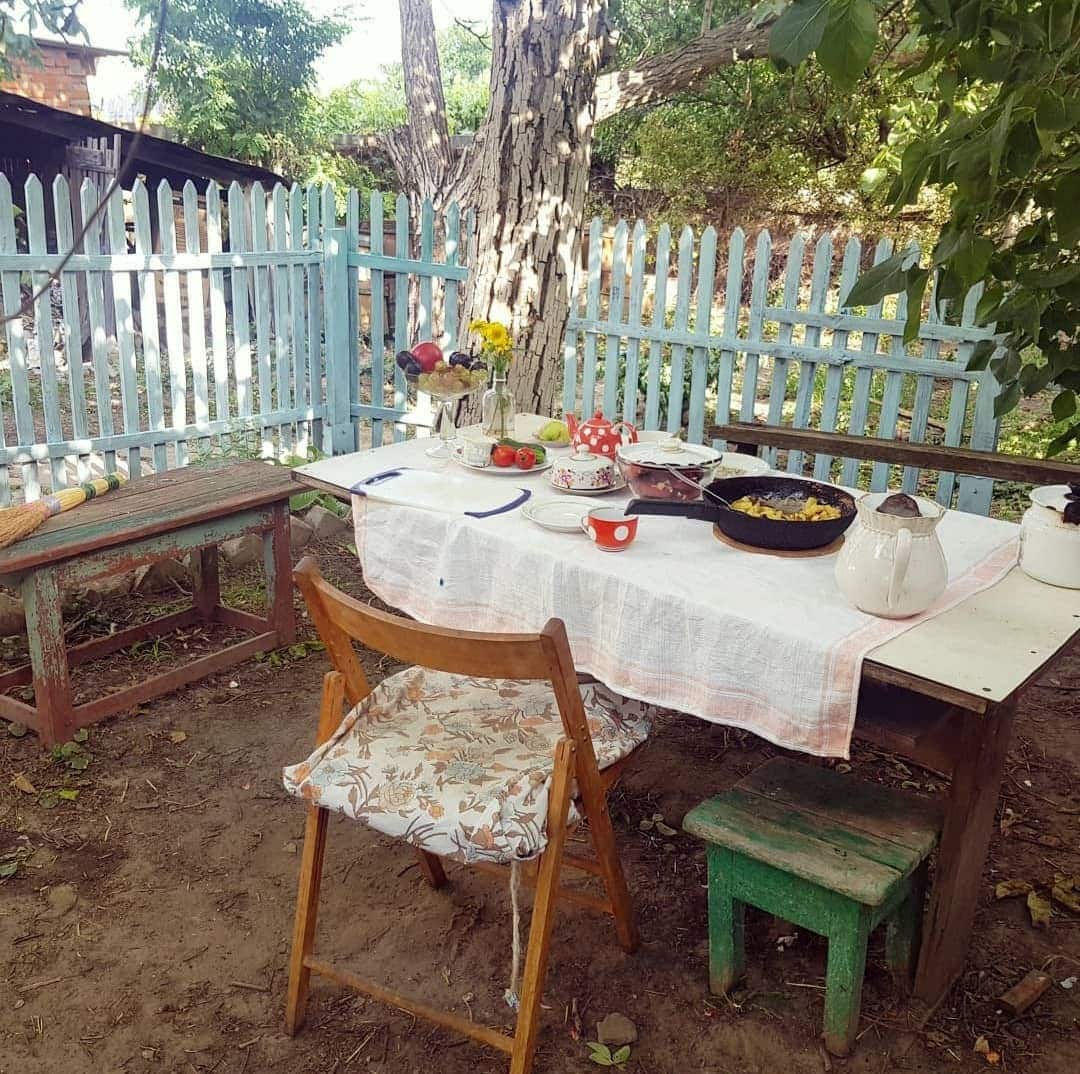 A table in a fenced garden laid out for breakfast.