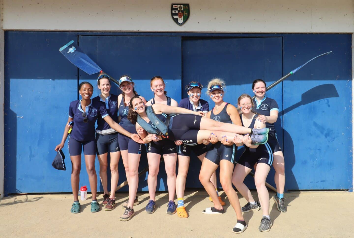 Photo of W1 crew posing in a line holding a crew member. All are dressed in their kit