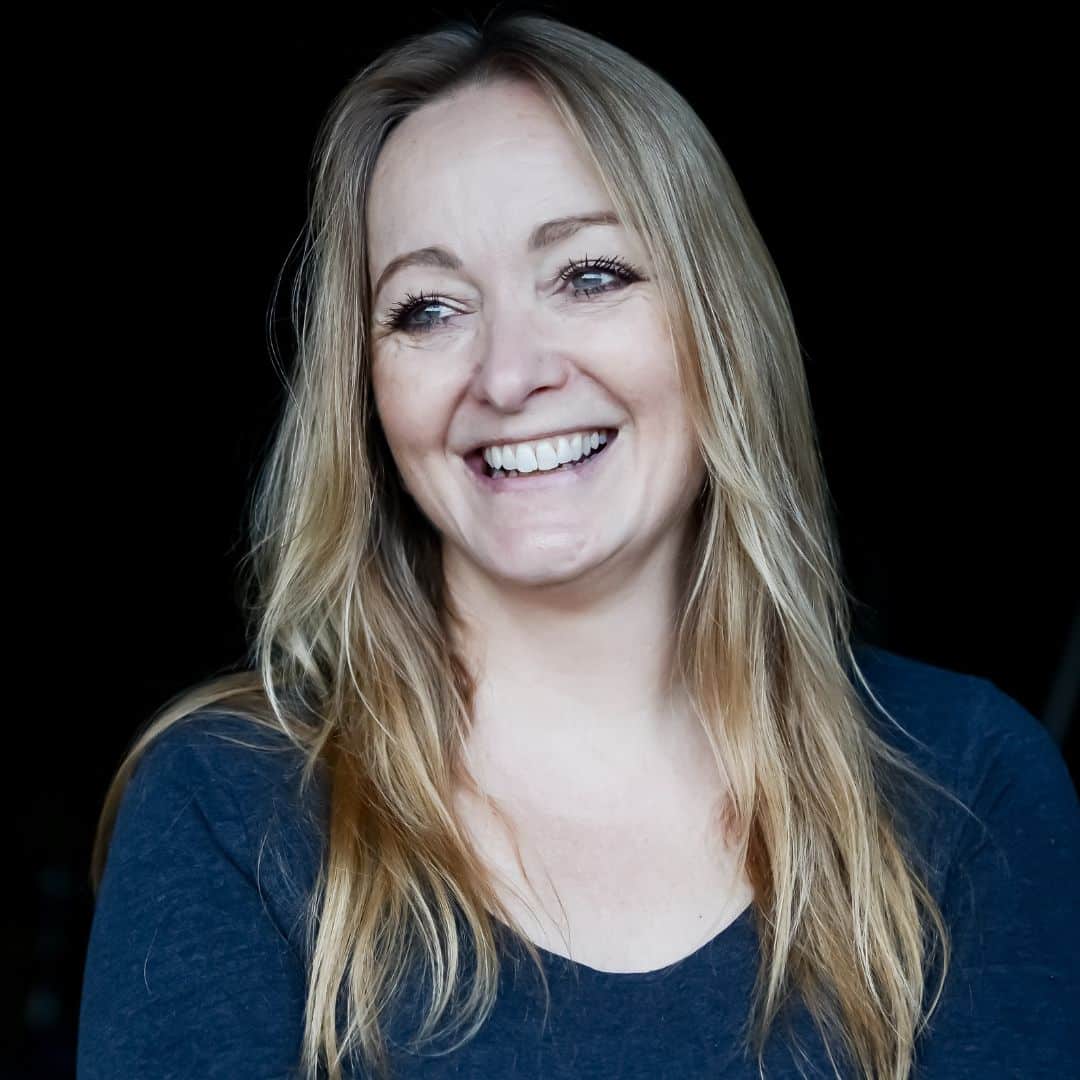 Photo of Lynn Shepherd wearing a blue shirt, standing against a black background