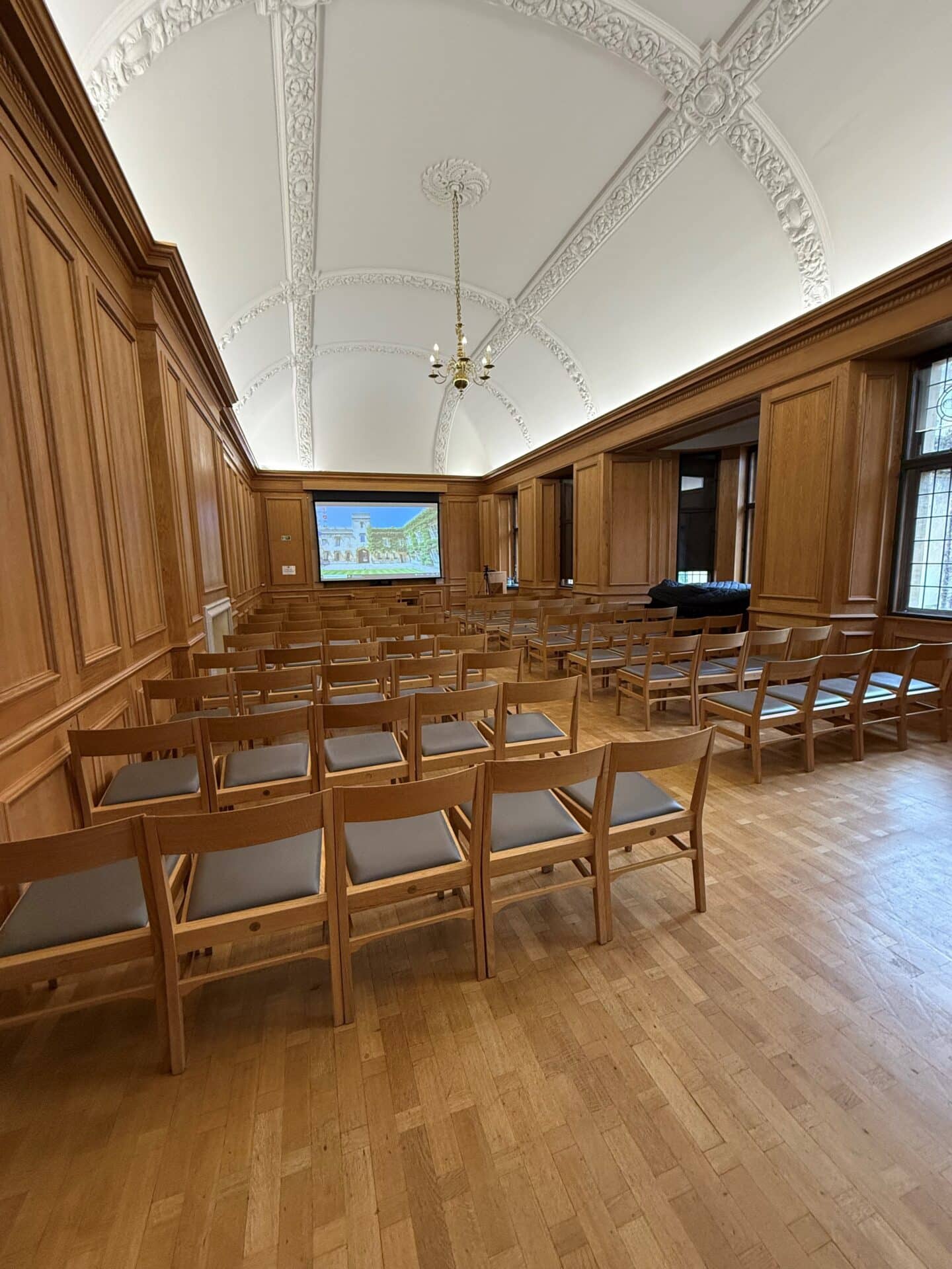 Photograph of the Oakeshott Room, with a large number of chairs facing a projector screen