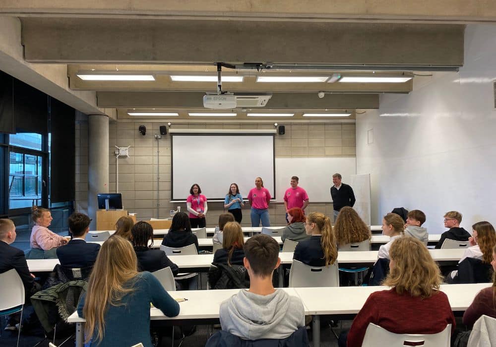 Photo of students sitting at long tables watching a lecture