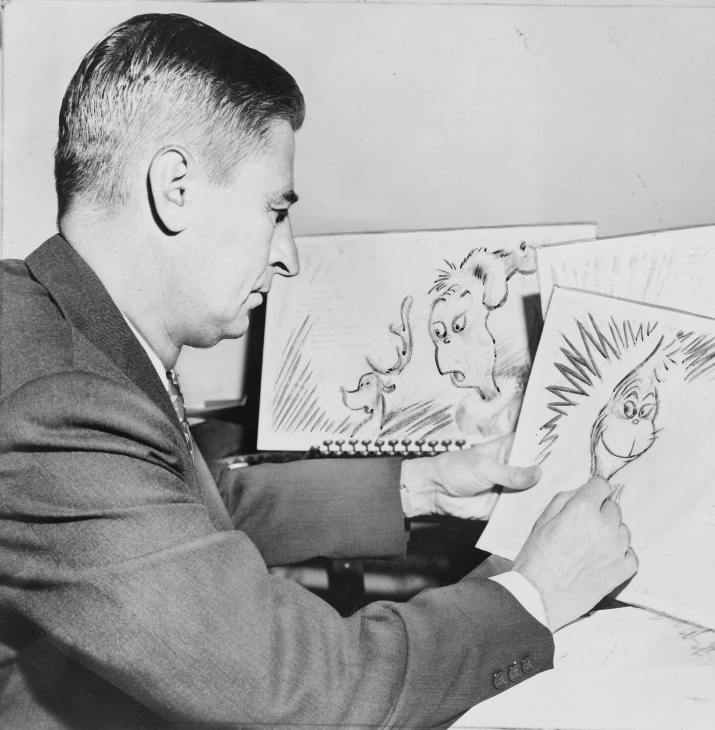 Greyscale image of Dr Seuss sketching the Grinch