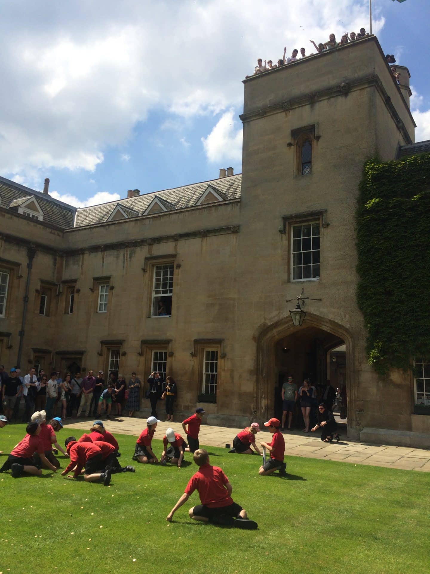 Picture from Ascension Day of schoolchildren picking up coins from the grass of the Lincoln College Front Quad, thrown by people from the Tower above