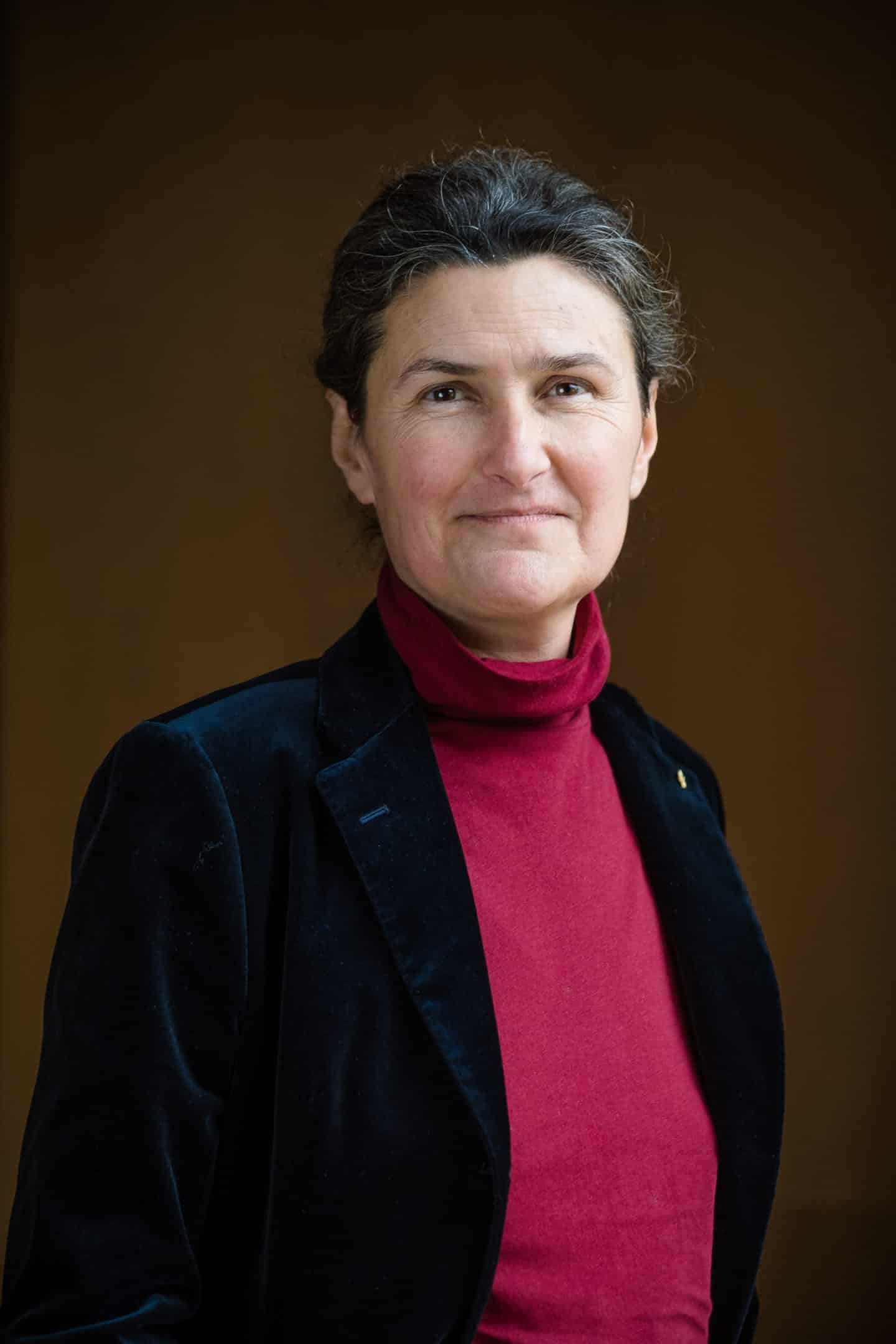 Headshot of Professor Cristina Dondi, a woman in a red sweater and black coat