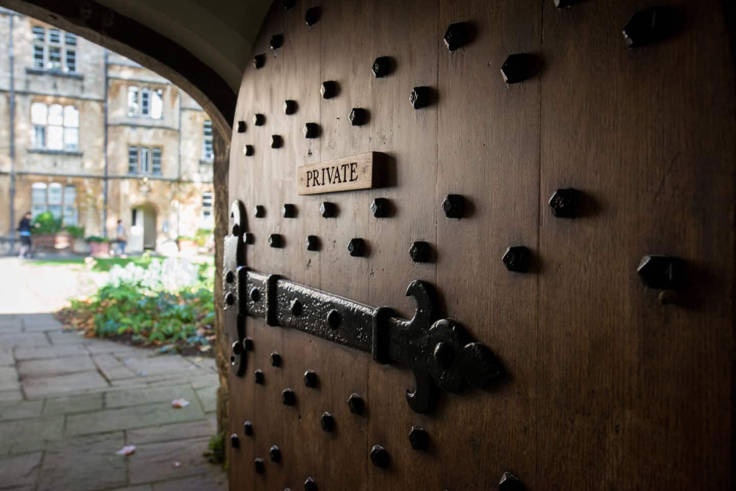 Large wooden door marked 'private' opening up into Grove Quad