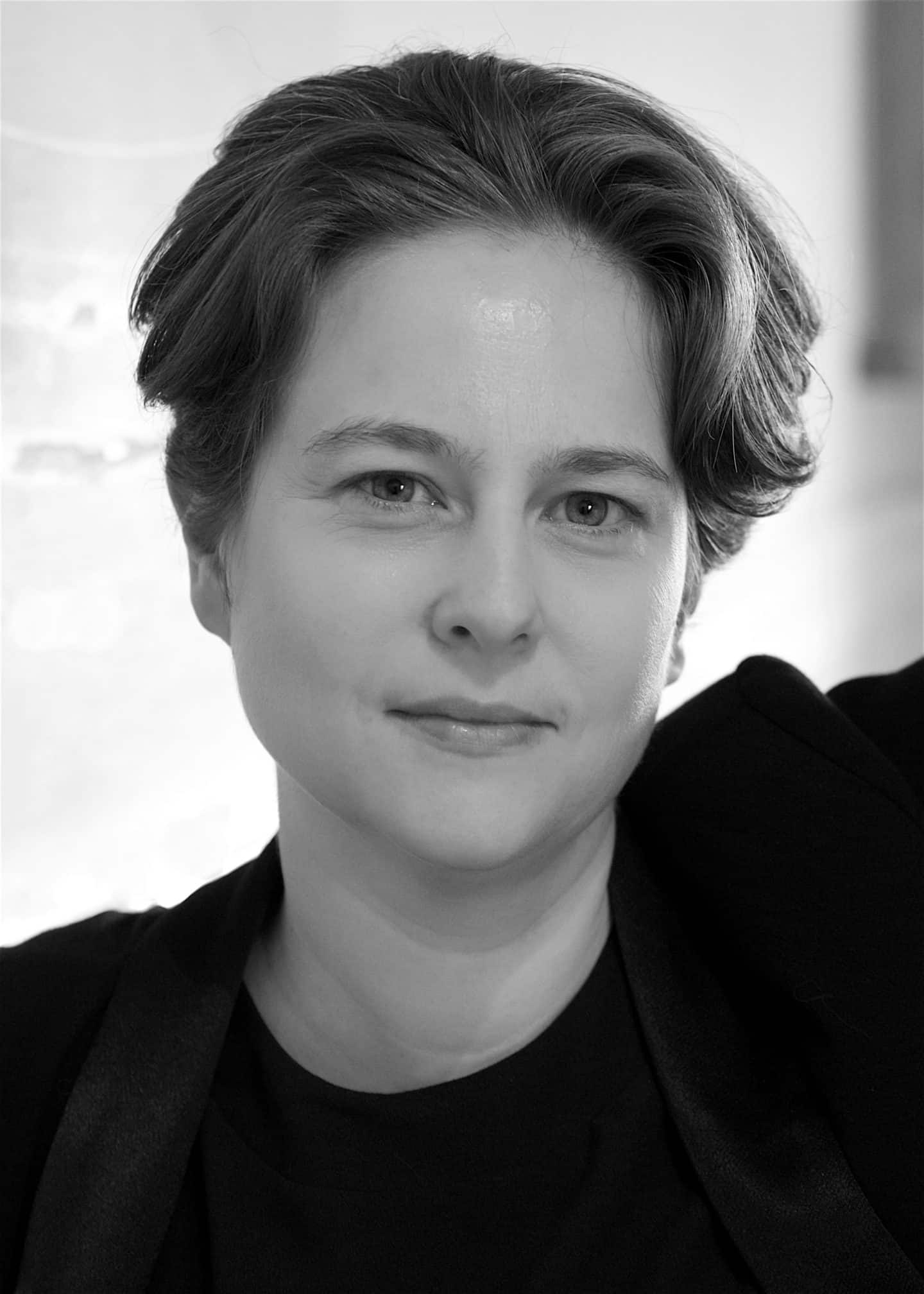 Greyscale photograph of Emily Howard, a woman in a dark top and jacket