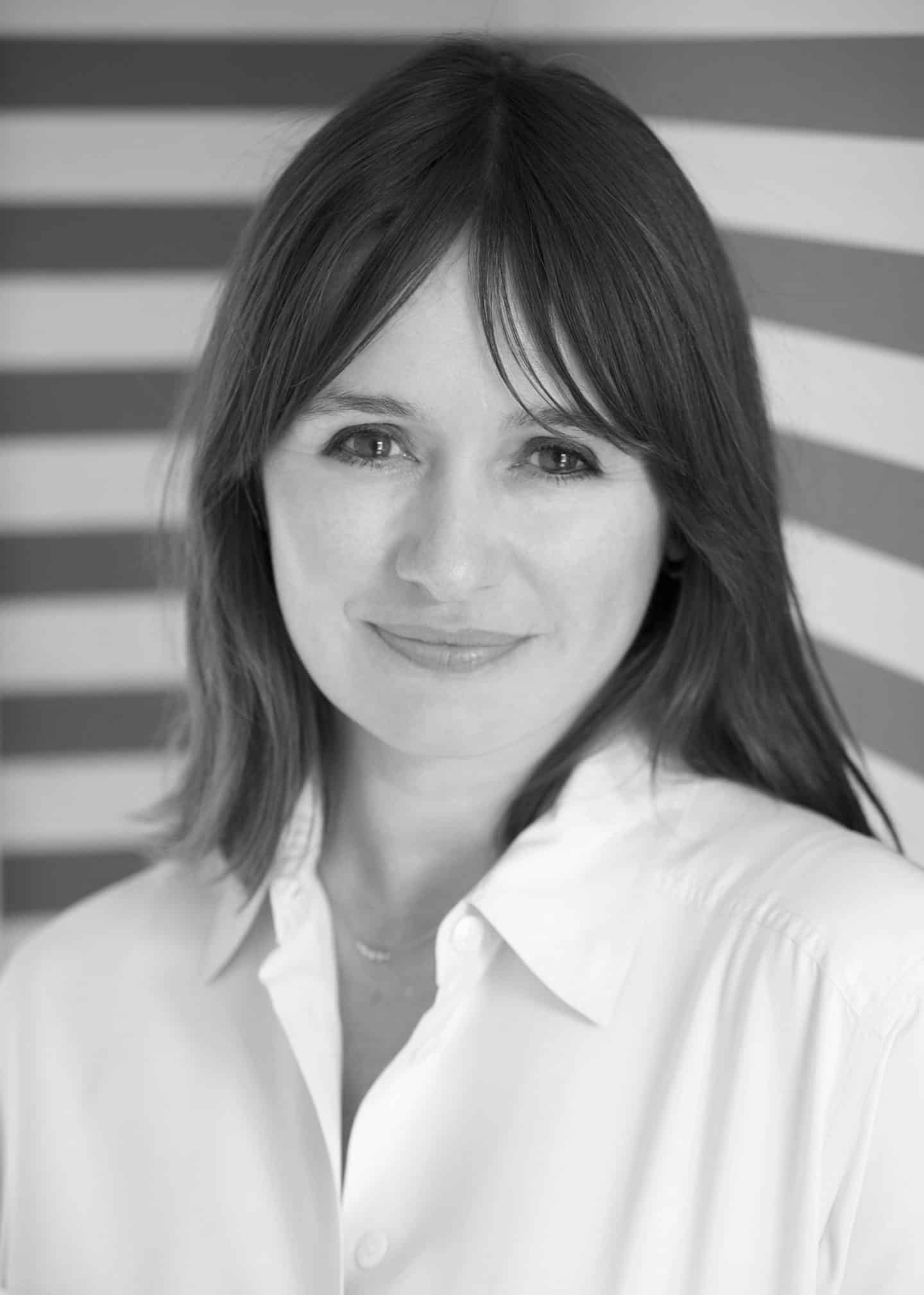 Greyscale photograph of Emily Mortimer, a woman in a white shirt