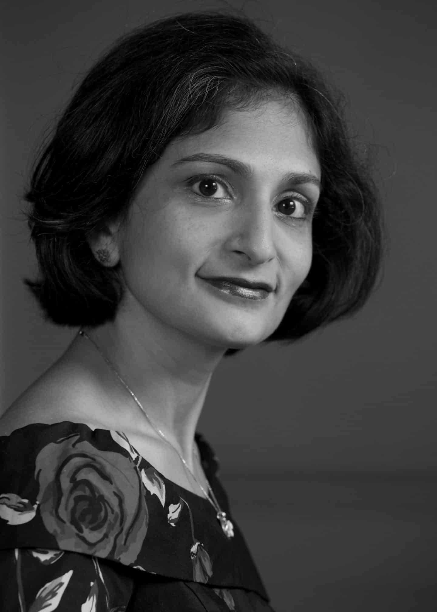 Greyscale photograph of Meena Seshamani, a woman in a floral top and necklace