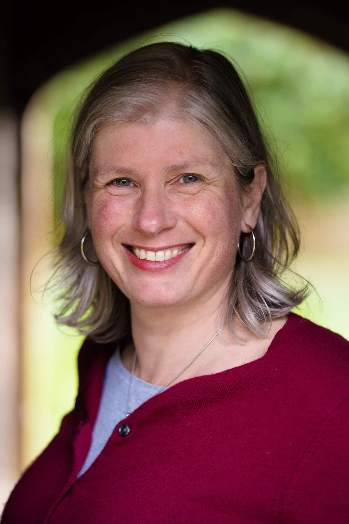 Headshot of Michele McCartney, a woman in a maroon top and necklace