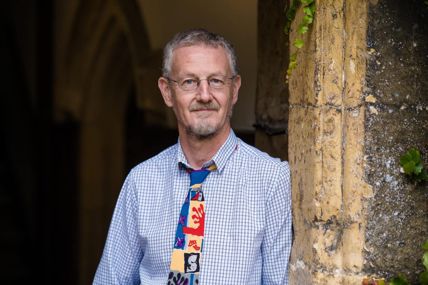 Headshot of Mike White, a man in glasses, a shirt and a colourful tie