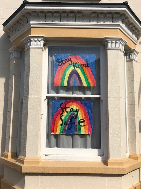 NHS rainbow posters in a window reading 'stay kind' and 'stay safe'