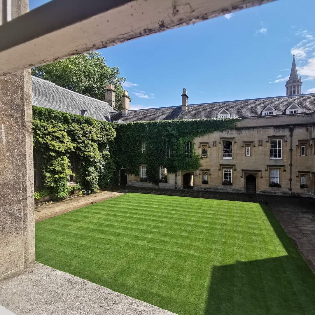 Photograph taken through an open window of a Lincoln College quad with clean green lawn