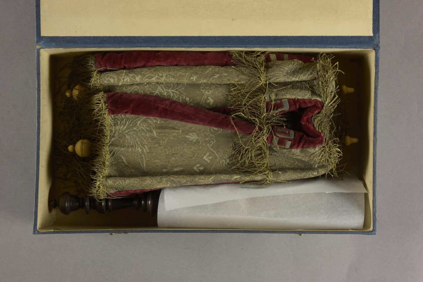 The white parchment scroll and its red and gold mantle cover are snugly nestled in a box