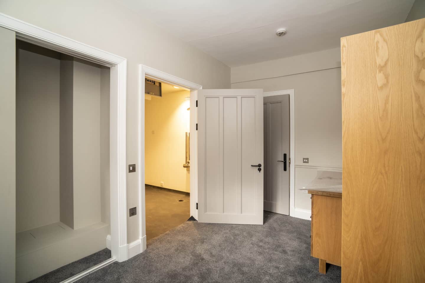 Part of a room with a wardrobe, chest of drawers, and an open door leading outside