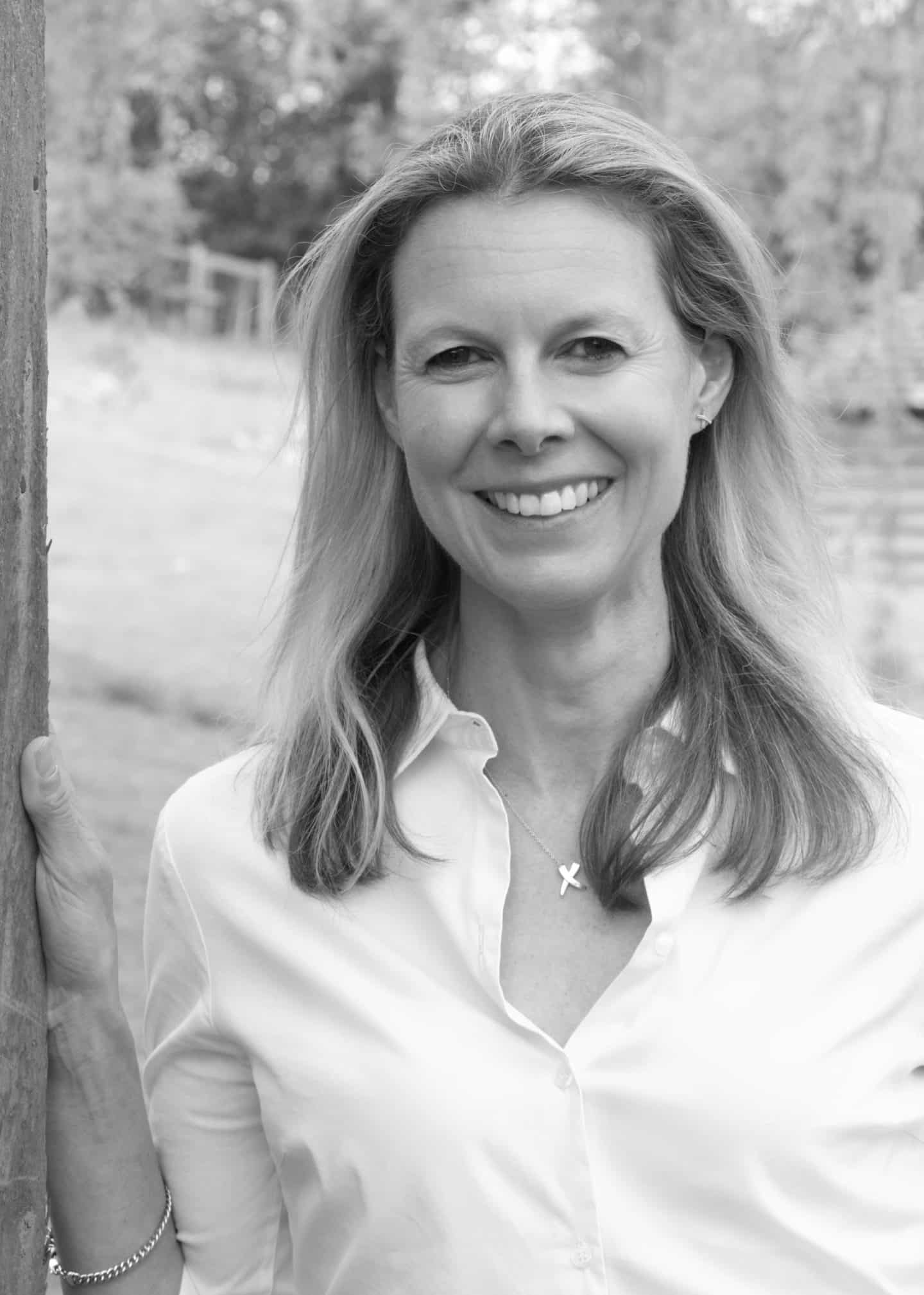Greyscale photograph of Steph Cook, a woman in a white shirt and necklace