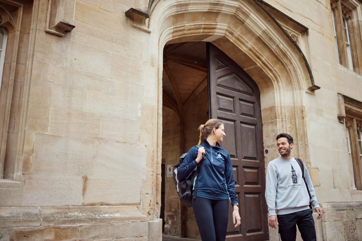 Two students leaving the main entrance of Lincoln College
