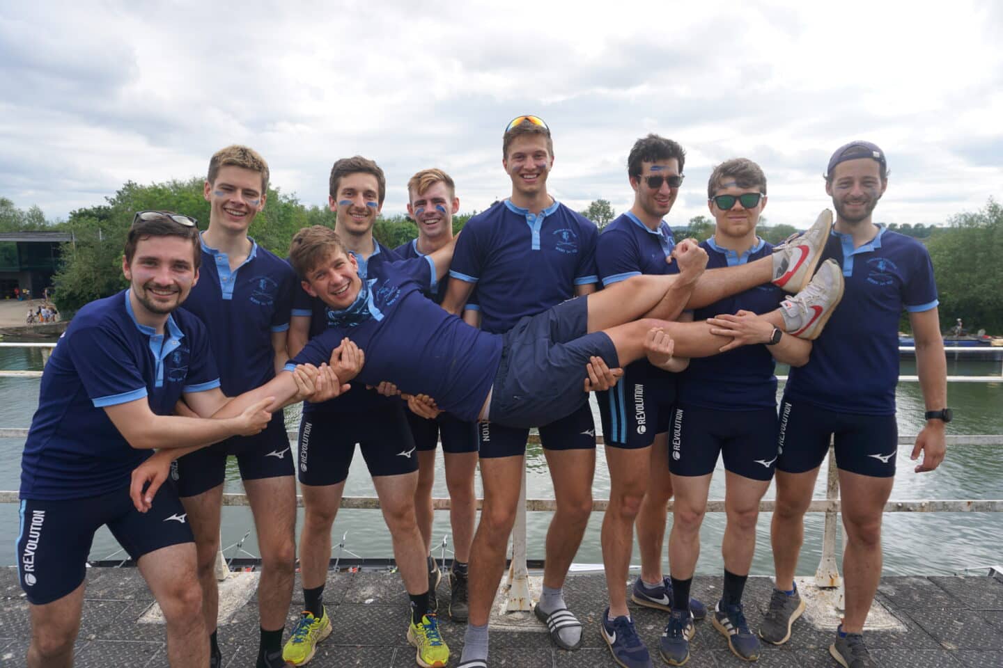 The M1 crew, all dressed in blue, smiling and holding up on member.