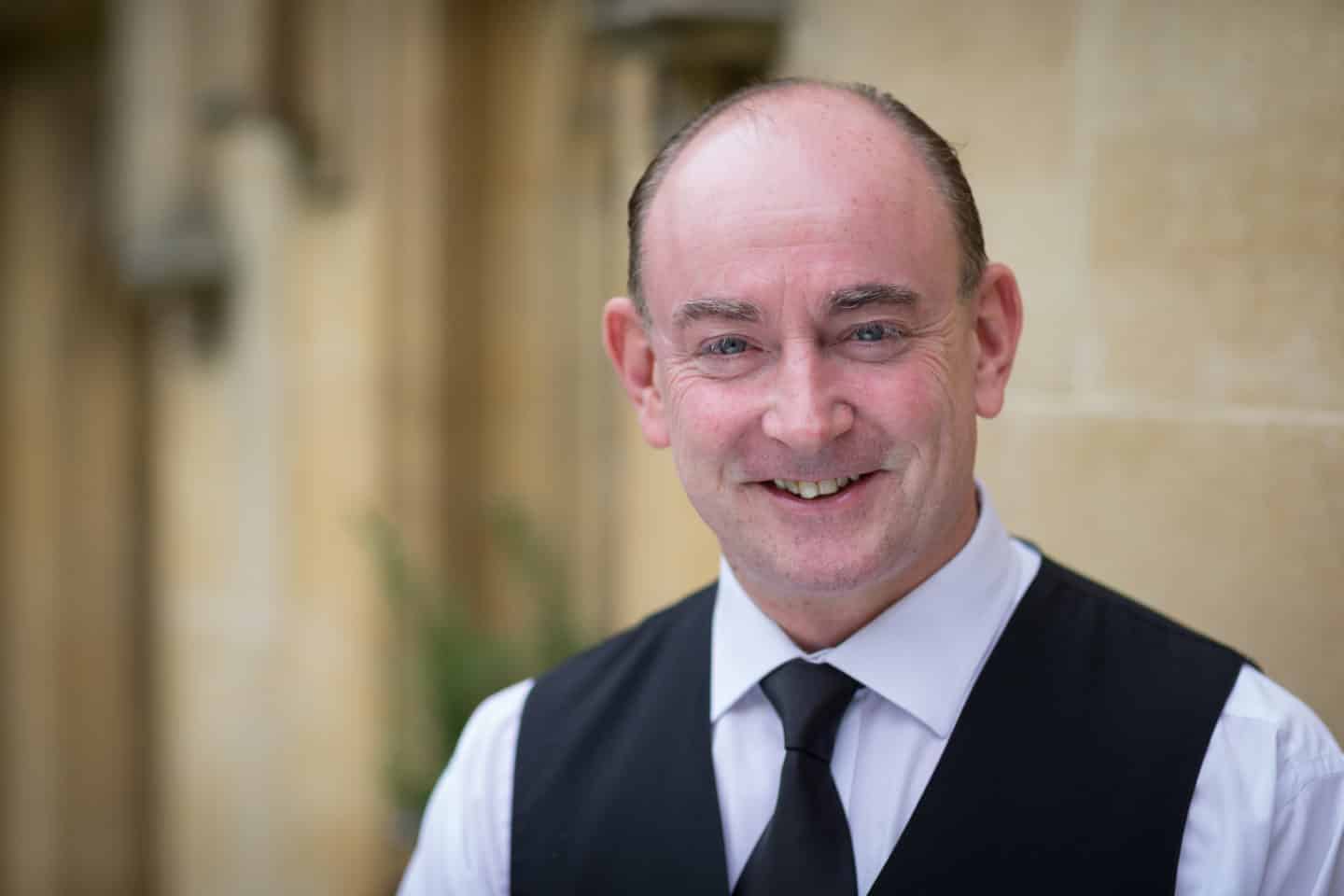 Headshot of the Butler Tony Daly in a white shirt, black tie and waistcoat